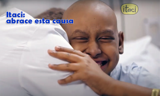 Imagem de uma criança sem cabelos, em tratamento contra o câncer, sorrindo abraçada ao seu médico
