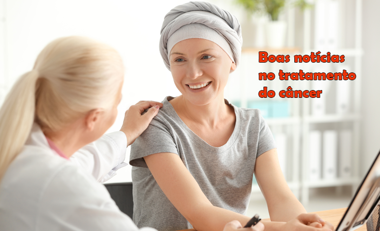 Imagem de uma médica colocando a mão esquerda sobre o ombro da sua paciente oncológica, que usa umm lenço cinza na cabeça e sorri para a médica