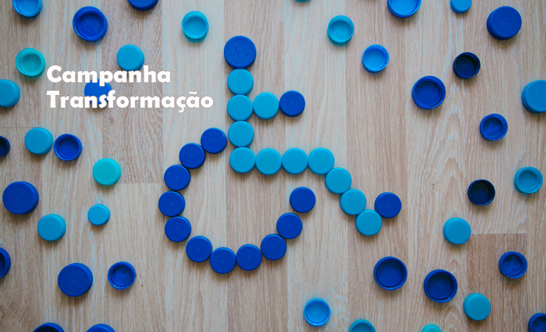 Imagem de tampinhas azuis de garrafas pet, dispostas formando o símbolo da pessoa com deficiência em uma cadeira de rodas